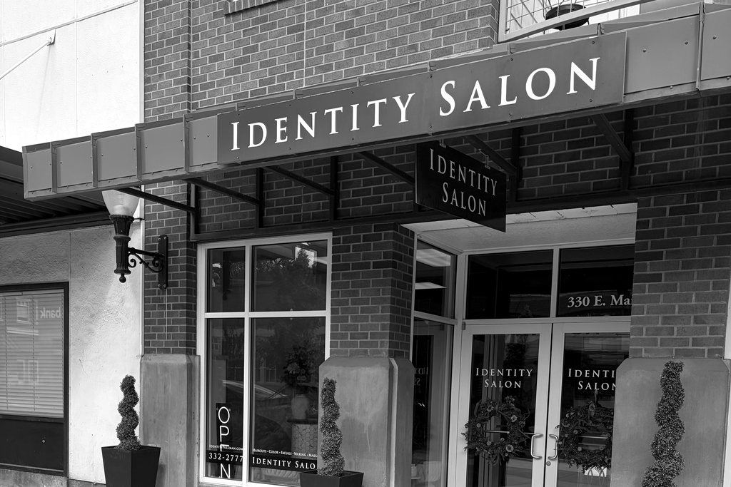 The Identity Salon storefront on East Main Street, with the green awning and planters